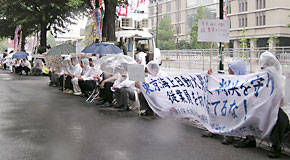 写真：雨の中会社回答を待つ行動参加